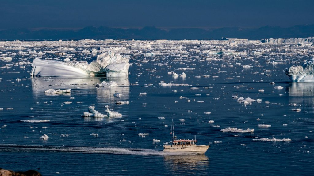 Small boat navigating through broken ice in a dark Arctic sea