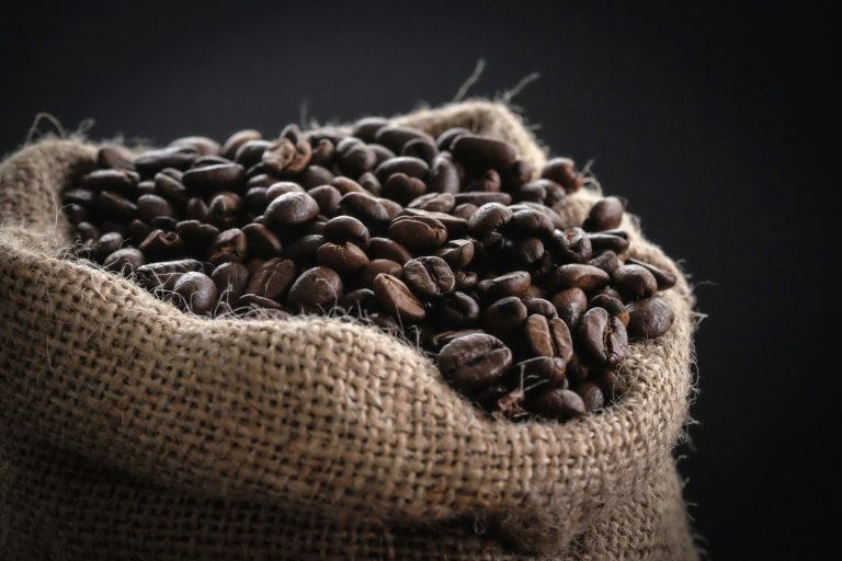 Roasted coffee beans spilling from a hessian sack