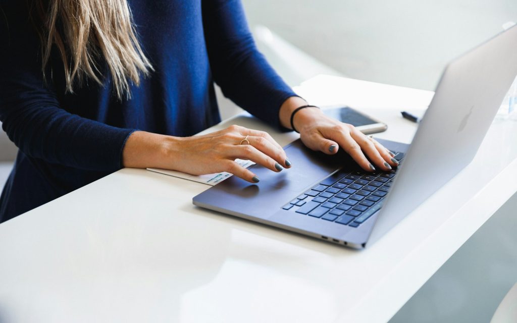 Editor typing on a laptop at a bright desk