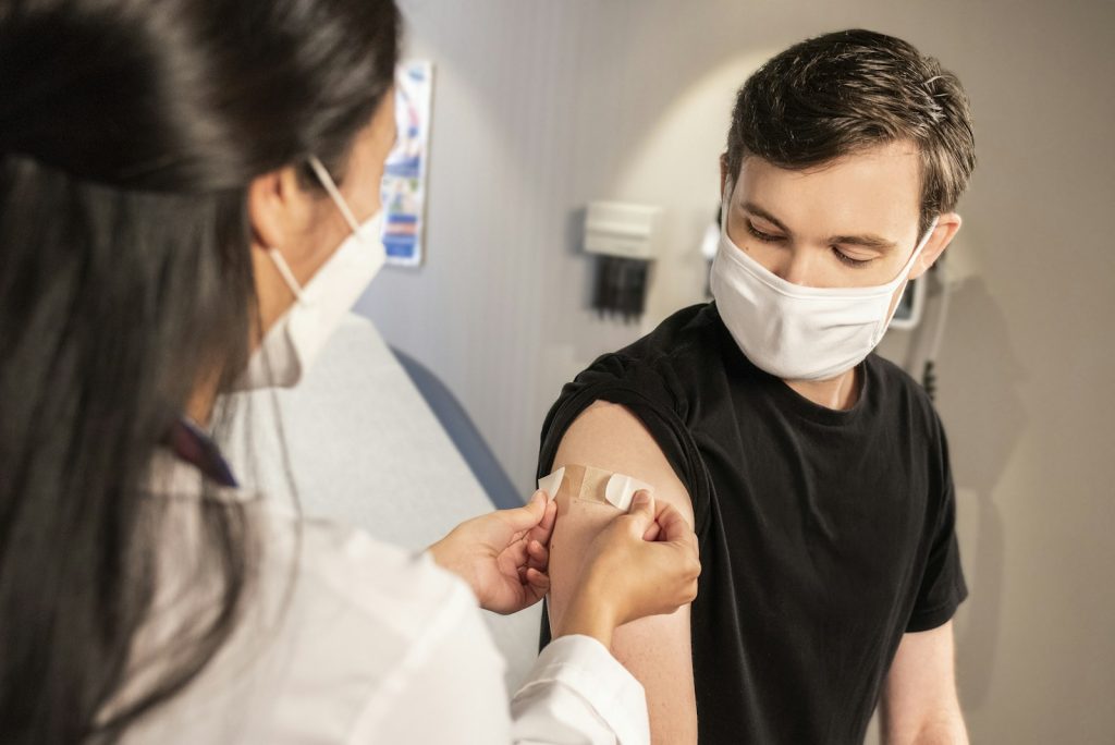 A health worker puts a bandage on a man's arm after a vaccination