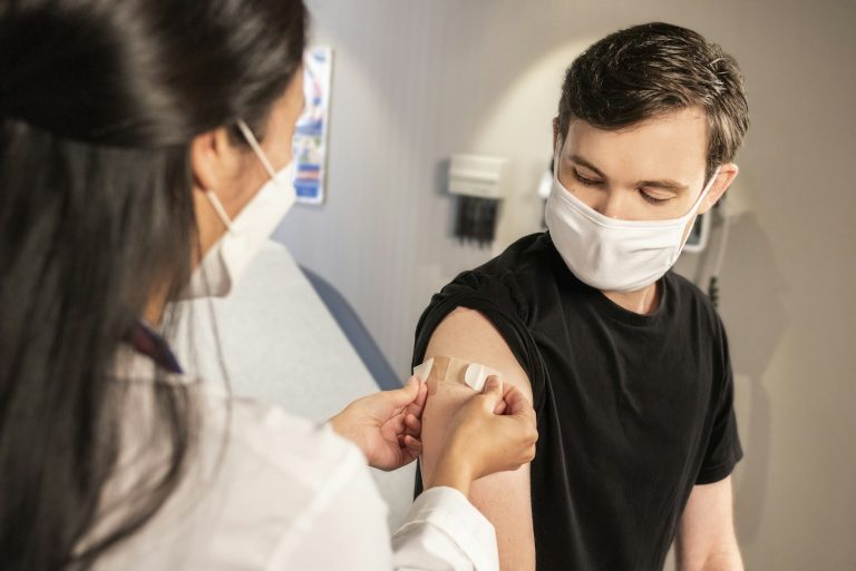 A health worker puts a bandage on a man's arm after a vaccination