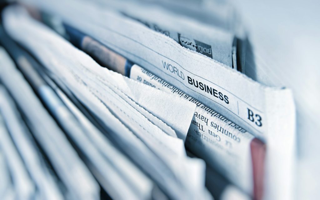 Stack of folded newspapers with business headlines