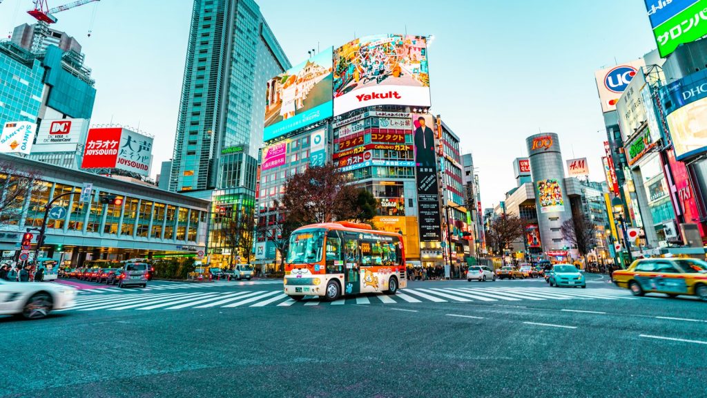 Bus crossing a busy street lined with shops in Tokyo, Japan