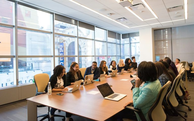 Editorial team meeting around a table with laptops