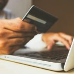 Person holding a payment card while shopping online on a laptop