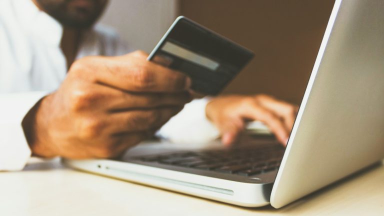 Person holding a payment card while shopping online on a laptop
