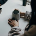 Two people talking over mugs of coffee at a table